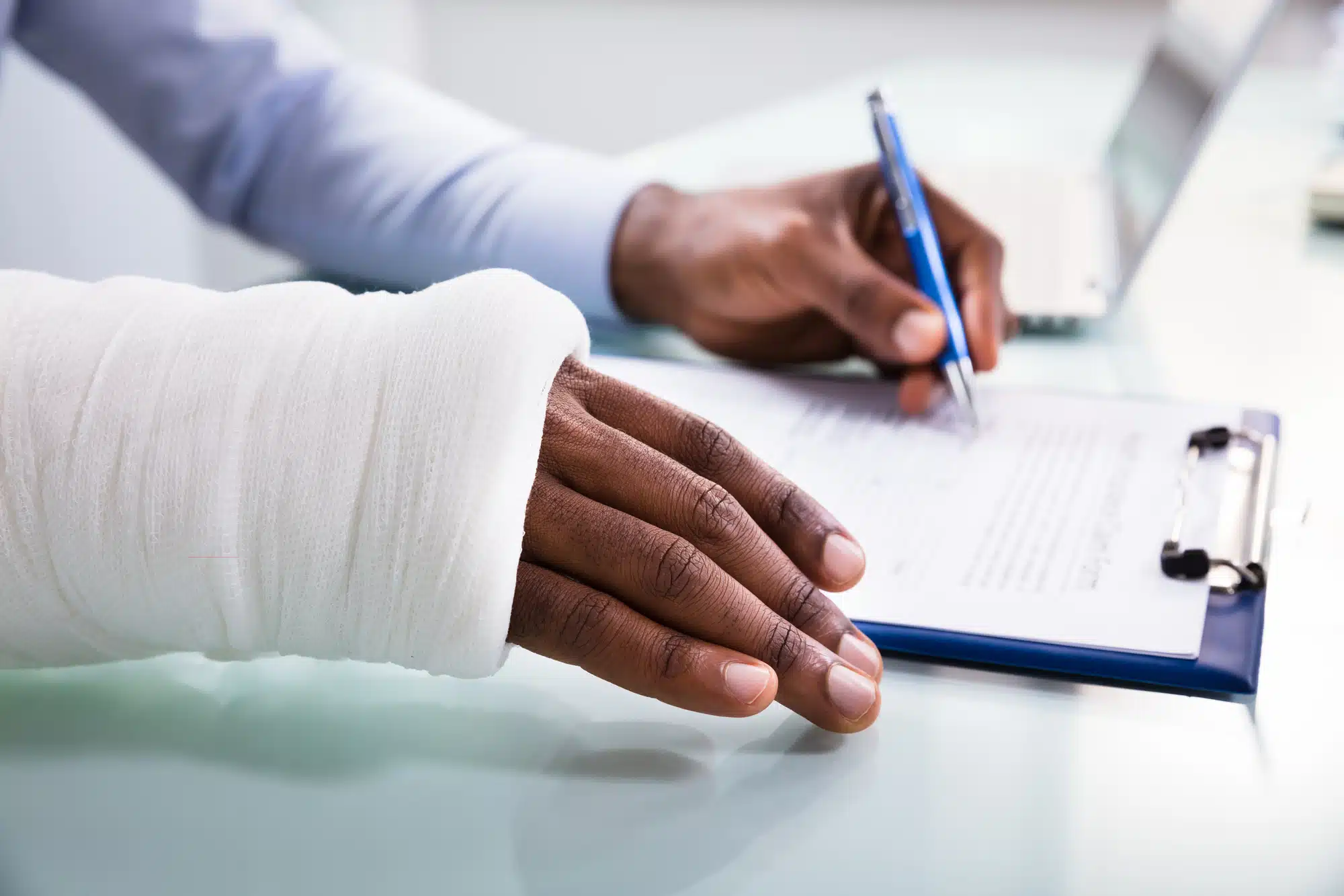 Learn more about the best workers comp insurance for small business; image of someone filling out insurance form with a bandaged hand