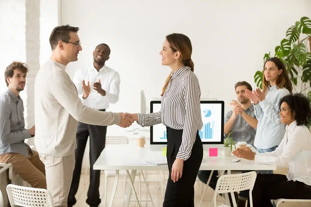 team congratulating a woman on merit pay increase and performance