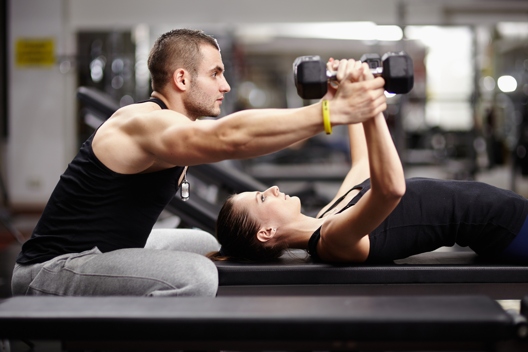 Personal trainer helping woman with weights: Do you need personal trainer insurance?